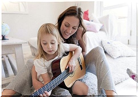 mother helping daughter play guitar