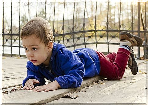 little boy lying on his stomach outside