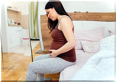 pregnant woman sitting on the edge of bed