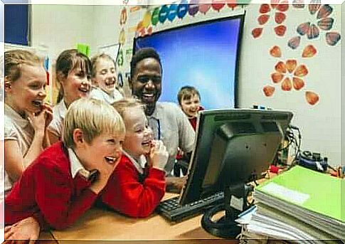 children and teacher laughing at something on computer