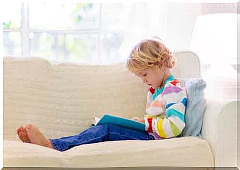 Child reading book on sofa