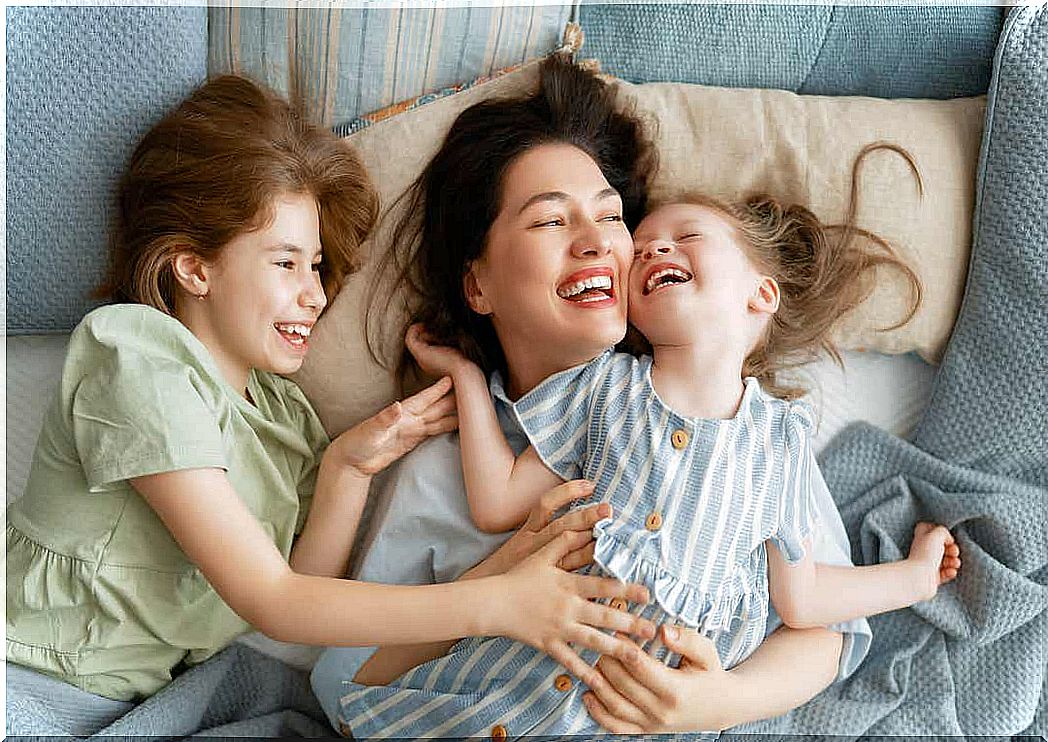 A mother cuddling in bed with her two young daughters