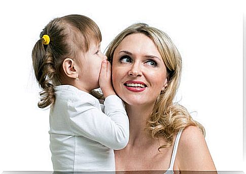 child whispering into mother's ear