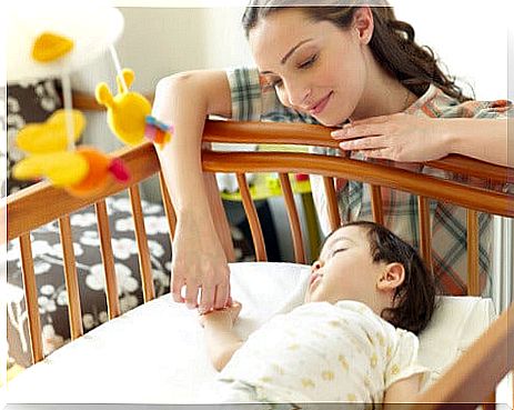 mother looking at her sleeping child in a crib