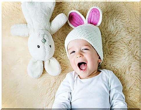 small child with rabbit hat and rabbit teddy bear next to him