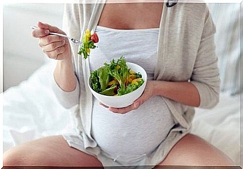 Pregnant woman eating a bowl of salad