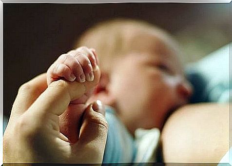 breastfeeding baby holding his mother's finger