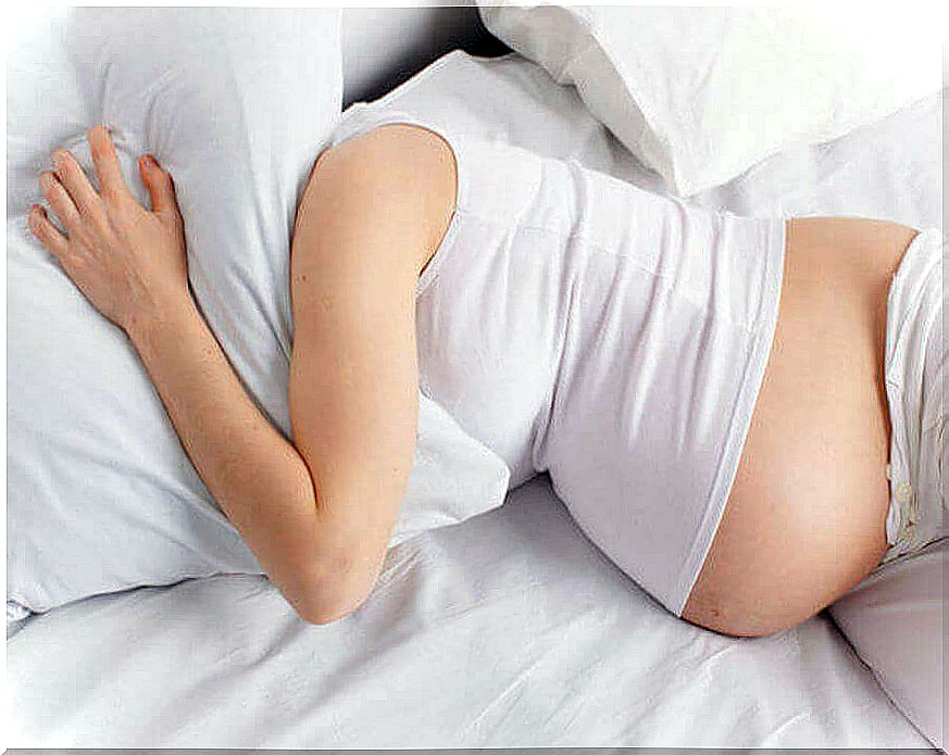 Pregnant woman lying in bed with discomfort due to pelvic discharge.