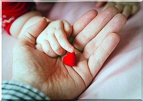 baby finger touching heart figure in adult hand