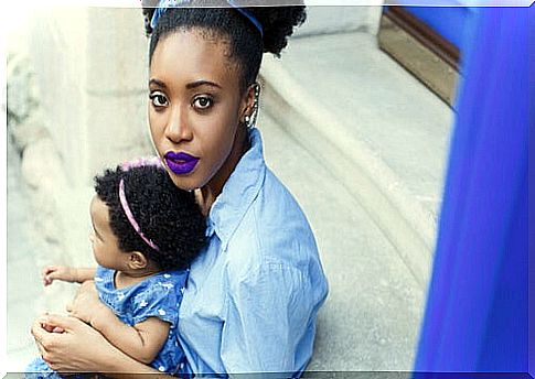 African American mother with purple lipstick and baby in lap